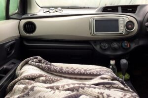 電気毛布を掛けて、車内で過ごしている人の画像